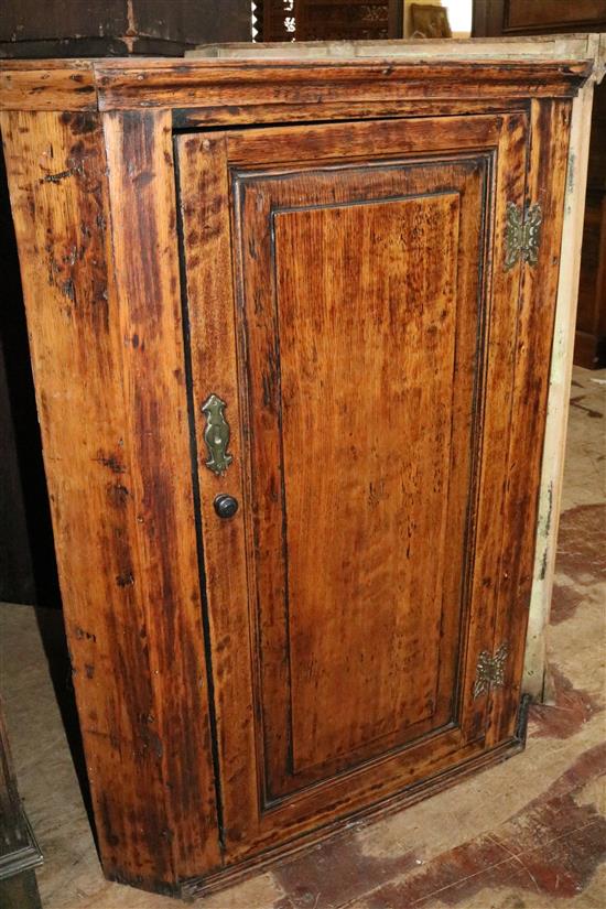 An early 19th century panelled oak hanging corner cupboard